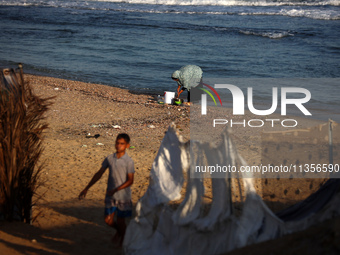 A Palestinian woman is washing kitchenware on the beach in Deir el-Balah, central Gaza Strip, on June 24, 2024, amid the ongoing conflict be...