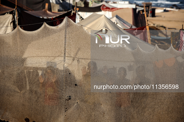 Displaced Palestinian children are looking outside their tent at the beach in Deir el-Balah, central Gaza Strip, on June 24, 2024, amid the...