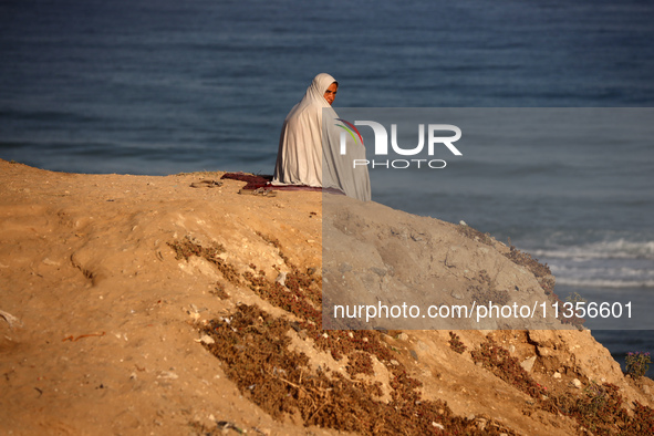 A displaced Palestinian woman is being seen on the beach in Deir el-Balah in the central Gaza Strip on June 24, 2024, amid the ongoing confl...