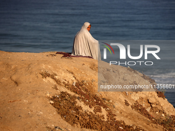 A displaced Palestinian woman is being seen on the beach in Deir el-Balah in the central Gaza Strip on June 24, 2024, amid the ongoing confl...