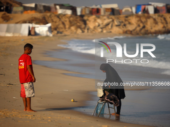 A Palestinian woman is washing clothes at the beach in Deir el-Balah, central Gaza Strip, on June 24, 2024, amid the ongoing conflict betwee...