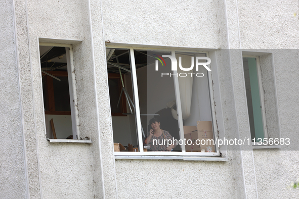 A woman is talking on the phone as seen through a knocked-out window at the Ivano-Frankivsk National Technical University of Oil and Gas, da...