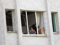 A woman is talking on the phone as seen through a knocked-out window at the Ivano-Frankivsk National Technical University of Oil and Gas, da...