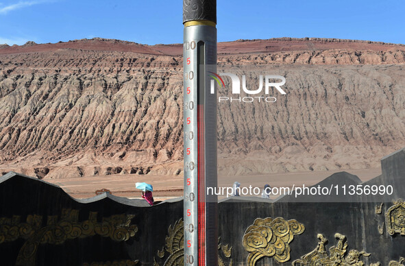 Tourists are visiting the Flaming Mountain scenic spot in Turpan, Xinjiang province, China, on June 24, 2024. A golden stick-shaped thermome...