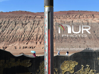 Tourists are visiting the Flaming Mountain scenic spot in Turpan, Xinjiang province, China, on June 24, 2024. A golden stick-shaped thermome...