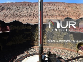 Tourists are visiting the Flaming Mountain scenic spot in Turpan, Xinjiang province, China, on June 24, 2024. A golden stick-shaped thermome...