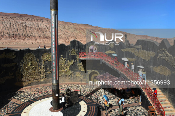 Tourists are visiting the Flaming Mountain scenic spot in Turpan, Xinjiang province, China, on June 24, 2024. A golden stick-shaped thermome...