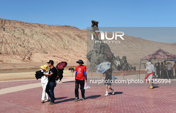 Tourists are visiting the Flaming Mountain scenic spot in Turpan, Xinjiang province, China, on June 24, 2024. A golden stick-shaped thermome...