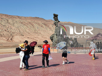 Tourists are visiting the Flaming Mountain scenic spot in Turpan, Xinjiang province, China, on June 24, 2024. A golden stick-shaped thermome...