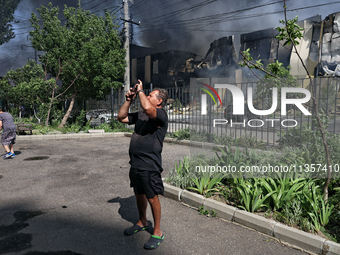 A man is taking a picture as smoke is rising from a warehouse destroyed as a result of a Russian missile strike in Odesa, Ukraine, on June 2...