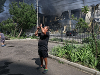 A man is taking a picture as smoke is rising from a warehouse destroyed as a result of a Russian missile strike in Odesa, Ukraine, on June 2...