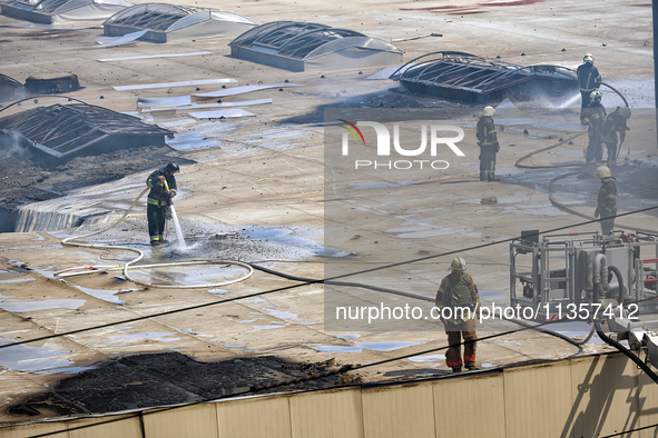 Firefighters are seen on the roof of a warehouse as they are putting out a fire caused by a Russian missile strike in Odesa, Ukraine, on Jun...