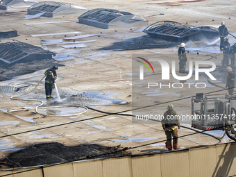 Firefighters are seen on the roof of a warehouse as they are putting out a fire caused by a Russian missile strike in Odesa, Ukraine, on Jun...