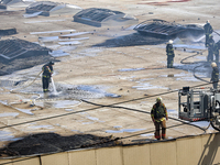 Firefighters are seen on the roof of a warehouse as they are putting out a fire caused by a Russian missile strike in Odesa, Ukraine, on Jun...