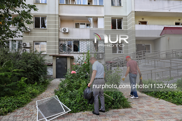 Men are cleaning the territory outside an apartment block where windows were knocked out by the shock wave from a Russian missile strike on...