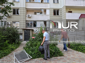 Men are cleaning the territory outside an apartment block where windows were knocked out by the shock wave from a Russian missile strike on...