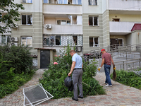 Men are cleaning the territory outside an apartment block where windows were knocked out by the shock wave from a Russian missile strike on...