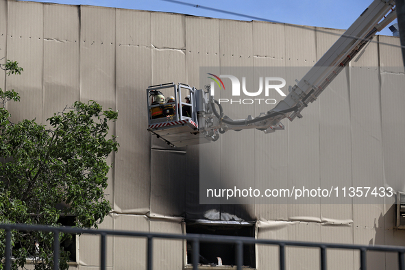 Firefighters in an aerial ladder platform are putting out a fire at a warehouse caused by a Russian missile attack on civilian infrastructur...