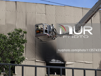 Firefighters in an aerial ladder platform are putting out a fire at a warehouse caused by a Russian missile attack on civilian infrastructur...