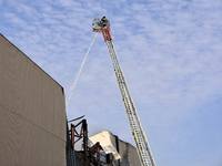 A firefighter in an aerial ladder platform is putting out a fire at a warehouse caused by a Russian missile attack on civilian infrastructur...