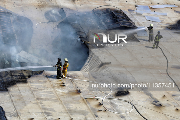 Firefighters are seen on the roof of a warehouse as they are putting out a fire caused by a Russian missile strike in Odesa, Ukraine, on Jun...