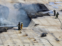 Firefighters are seen on the roof of a warehouse as they are putting out a fire caused by a Russian missile strike in Odesa, Ukraine, on Jun...