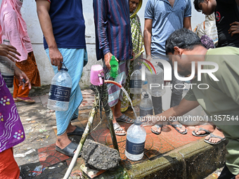 People are gathering around a roadside water pipeline to collect drinking water during a high-temperature weather day in Dhaka, Bangladesh,...