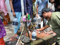 People are gathering around a roadside water pipeline to collect drinking water during a high-temperature weather day in Dhaka, Bangladesh,...