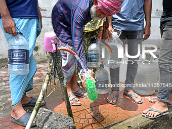 People are gathering around a roadside water pipeline to collect drinking water during a high-temperature weather day in Dhaka, Bangladesh,...