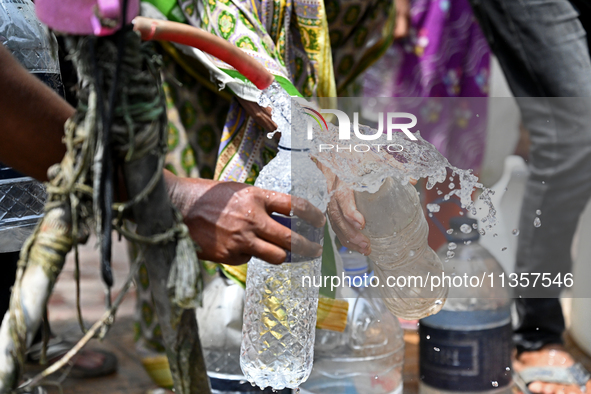 People are gathering around a roadside water pipeline to collect drinking water during a high-temperature weather day in Dhaka, Bangladesh,...