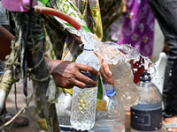 People are gathering around a roadside water pipeline to collect drinking water during a high-temperature weather day in Dhaka, Bangladesh,...