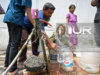 People are gathering around a roadside water pipeline to collect drinking water during a high-temperature weather day in Dhaka, Bangladesh,...