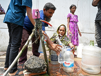 People are gathering around a roadside water pipeline to collect drinking water during a high-temperature weather day in Dhaka, Bangladesh,...