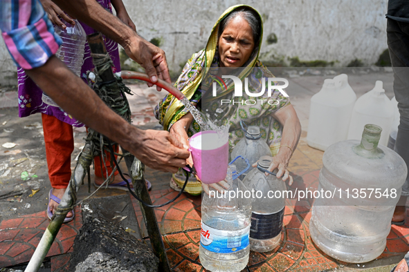 People are gathering around a roadside water pipeline to collect drinking water during a high-temperature weather day in Dhaka, Bangladesh,...