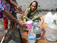 People are gathering around a roadside water pipeline to collect drinking water during a high-temperature weather day in Dhaka, Bangladesh,...