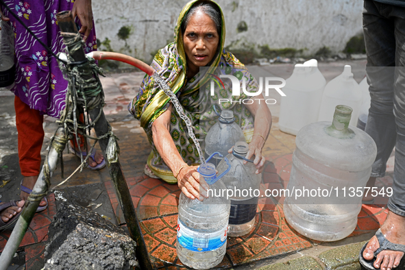 People are gathering around a roadside water pipeline to collect drinking water during a high-temperature weather day in Dhaka, Bangladesh,...