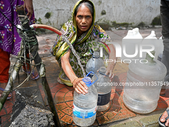 People are gathering around a roadside water pipeline to collect drinking water during a high-temperature weather day in Dhaka, Bangladesh,...