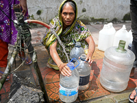 People are gathering around a roadside water pipeline to collect drinking water during a high-temperature weather day in Dhaka, Bangladesh,...