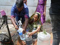 People are gathering around a roadside water pipeline to collect drinking water during a high-temperature weather day in Dhaka, Bangladesh,...