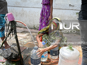 People are gathering around a roadside water pipeline to collect drinking water during a high-temperature weather day in Dhaka, Bangladesh,...