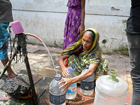 People are gathering around a roadside water pipeline to collect drinking water during a high-temperature weather day in Dhaka, Bangladesh,...