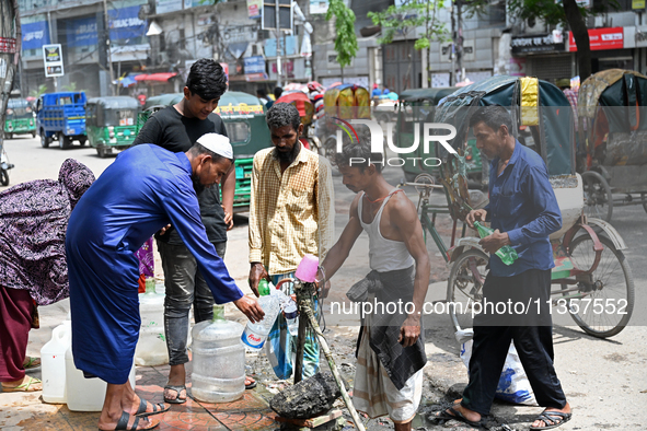 People are gathering around a roadside water pipeline to collect drinking water during a high-temperature weather day in Dhaka, Bangladesh,...