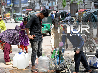 People are gathering around a roadside water pipeline to collect drinking water during a high-temperature weather day in Dhaka, Bangladesh,...