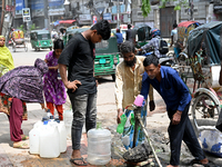 People are gathering around a roadside water pipeline to collect drinking water during a high-temperature weather day in Dhaka, Bangladesh,...