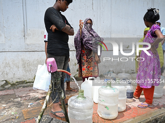 People are gathering around a roadside water pipeline to collect drinking water during a high-temperature weather day in Dhaka, Bangladesh,...