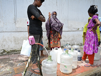 People are gathering around a roadside water pipeline to collect drinking water during a high-temperature weather day in Dhaka, Bangladesh,...