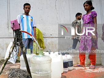 People are gathering around a roadside water pipeline to collect drinking water during a high-temperature weather day in Dhaka, Bangladesh,...