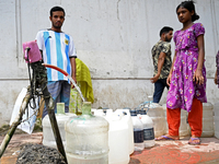 People are gathering around a roadside water pipeline to collect drinking water during a high-temperature weather day in Dhaka, Bangladesh,...