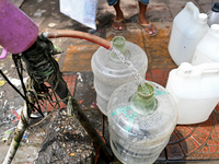 People are gathering around a roadside water pipeline to collect drinking water during a high-temperature weather day in Dhaka, Bangladesh,...