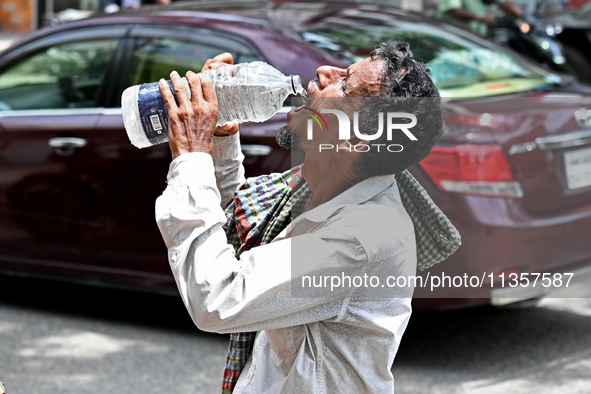 A rickshaw driver is drinking water from a roadside water pipeline during high temperature weather in Dhaka, Bangladesh, on June 24, 2024 